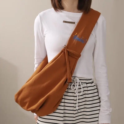 Portable cat carrier sling bag worn crossbody, stylish design for traveling with small dogs and pets.
